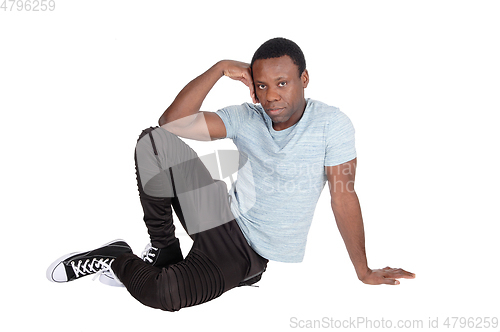 Image of Handsome African man sitting on floor resting