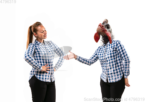 Image of Young handsome woman arguing with herself as a chicken on white studio background.