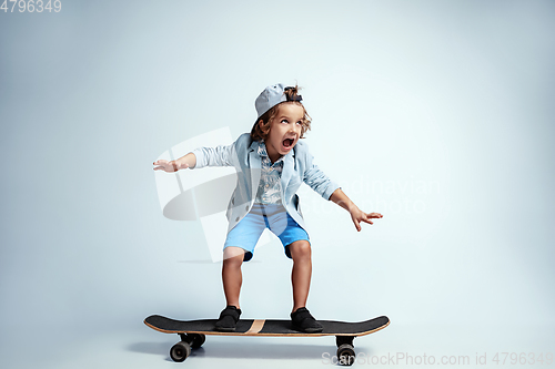 Image of Pretty young boy on skateboard in casual clothes on white studio background