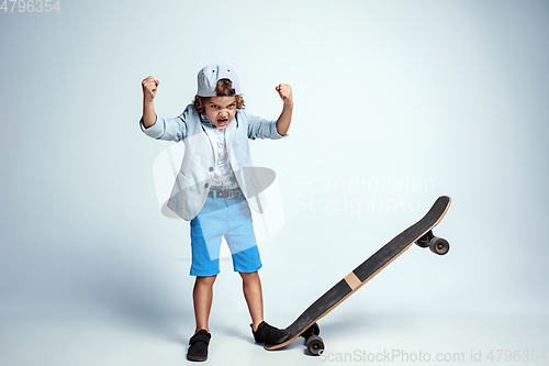 Image of Pretty young boy on skateboard in casual clothes on white studio background