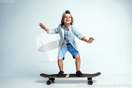 Image of Pretty young boy on skateboard in casual clothes on white studio background