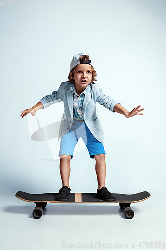 Image of Pretty young boy on skateboard in casual clothes on white studio background