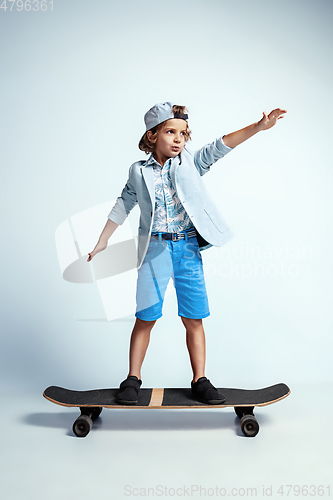 Image of Pretty young boy on skateboard in casual clothes on white studio background