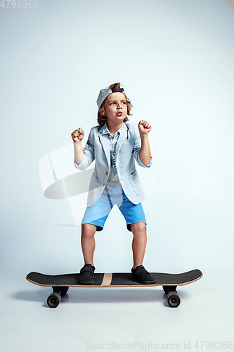 Image of Pretty young boy on skateboard in casual clothes on white studio background