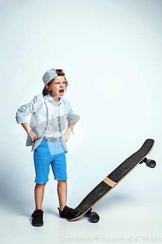 Image of Pretty young boy on skateboard in casual clothes on white studio background