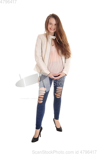 Image of Young woman standing in jeans and jacket