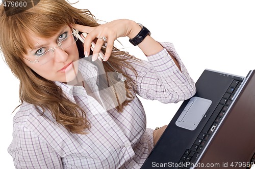 Image of The young woman in glasses sits with the laptop and phone. Isola