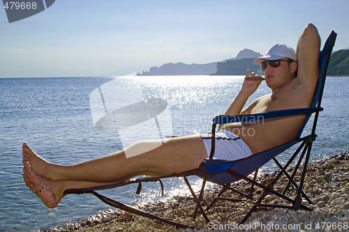 Image of The young man with a cigar has a rest on seacoast