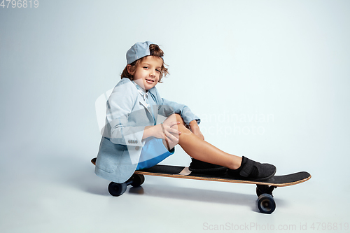 Image of Pretty young boy on skateboard in casual clothes on white studio background