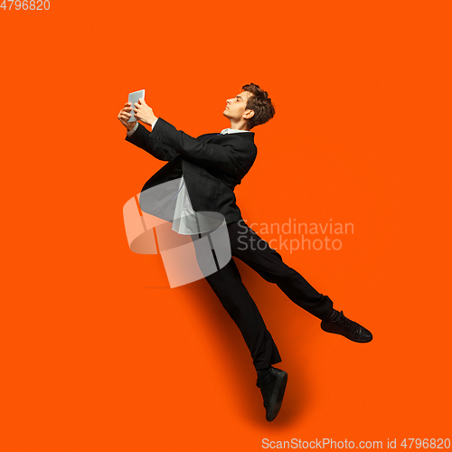 Image of Man in casual office style clothes jumping isolated on studio background