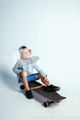 Image of Pretty young boy on skateboard in casual clothes on white studio background