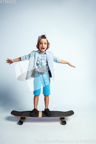 Image of Pretty young boy on skateboard in casual clothes on white studio background