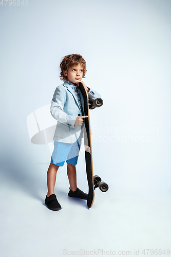 Image of Pretty young boy on skateboard in casual clothes on white studio background