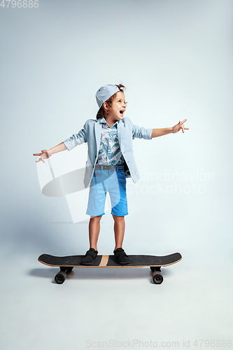 Image of Pretty young boy on skateboard in casual clothes on white studio background