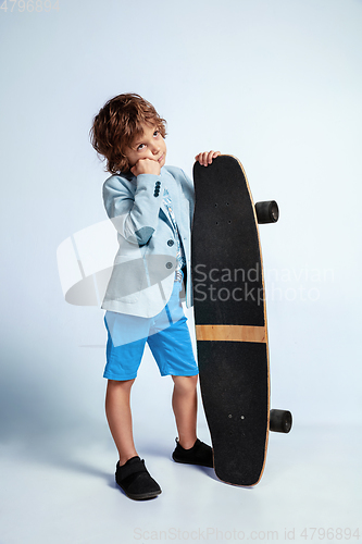 Image of Pretty young boy on skateboard in casual clothes on white studio background