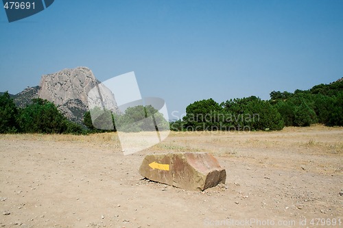 Image of Yellow arrow on a stone, specifying a direction in mountains