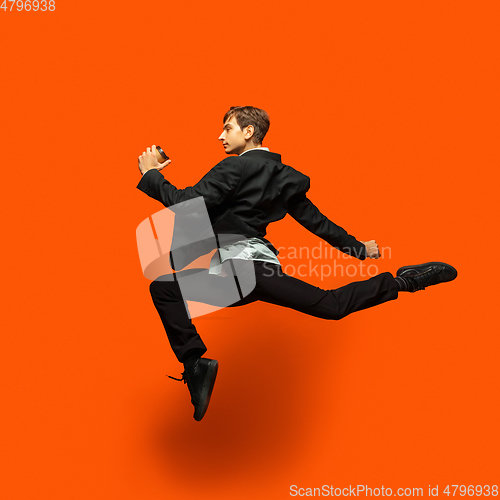 Image of Man in casual office style clothes jumping isolated on studio background