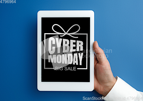 Image of Male hand holding tablet with cyber monday words on blue background