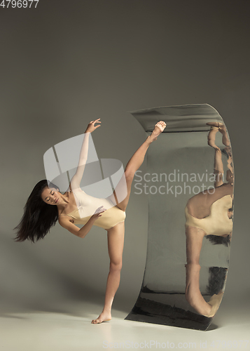 Image of Young and stylish modern ballet dancer on brown background