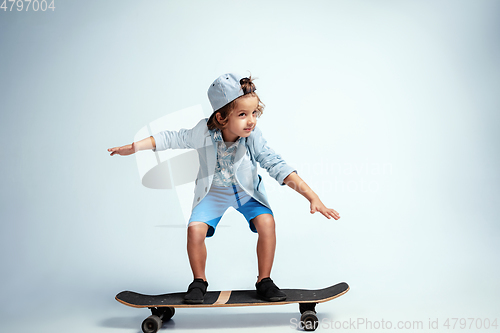 Image of Pretty young boy on skateboard in casual clothes on white studio background