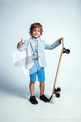 Image of Pretty young boy on skateboard in casual clothes on white studio background