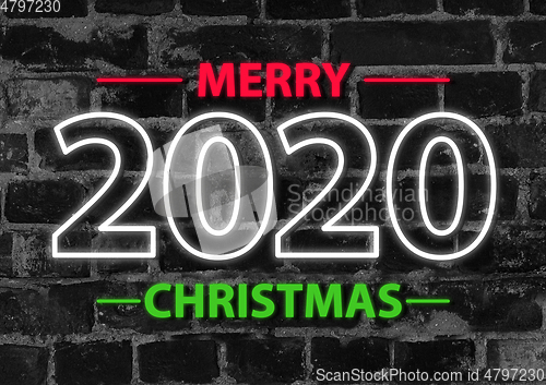 Image of 2020 in neon multi colour, parallel lines pattern on black brick background