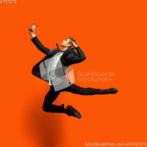 Image of Man in casual office style clothes jumping isolated on studio background