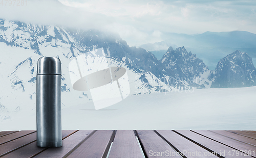 Image of Thermos with tea or coffee and landscape of mountains on background