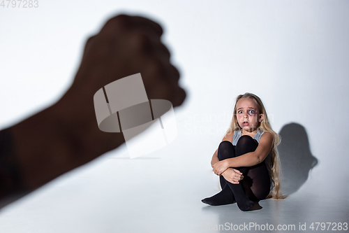 Image of Sad and frightened little girl with bloodshot and bruised eyes sitting scared