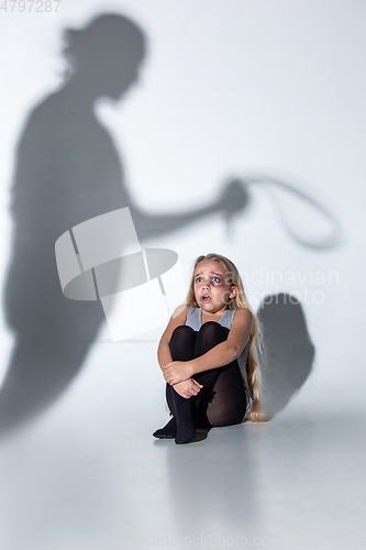 Image of Sad and frightened little girl with bloodshot and bruised eyes sitting scared