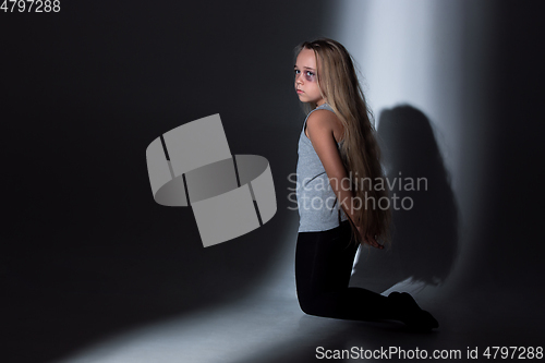 Image of Sad and frightened little girl with bloodshot and bruised eyes sitting scared