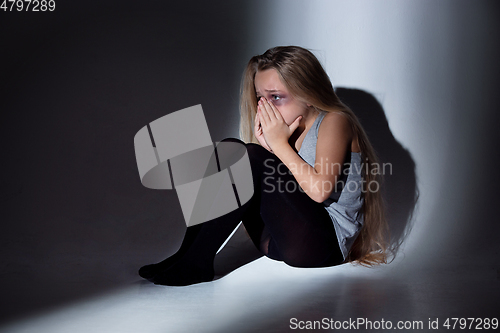 Image of Sad and frightened little girl with bloodshot and bruised eyes sitting scared