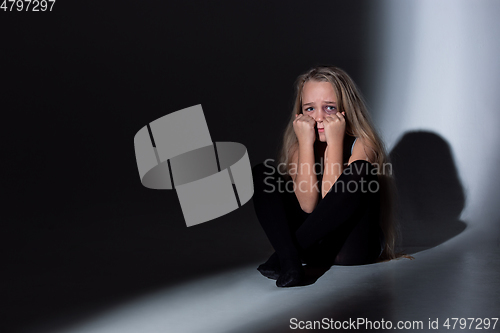 Image of Sad and frightened little girl with bloodshot and bruised eyes sitting scared