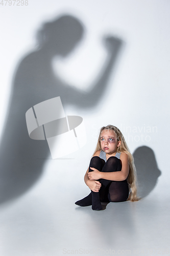 Image of Sad and frightened little girl with bloodshot and bruised eyes sitting scared