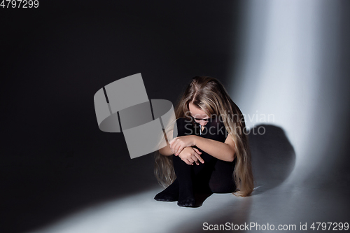 Image of Sad and frightened little girl with bloodshot and bruised eyes sitting scared