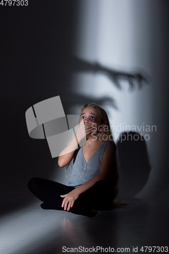 Image of Sad and frightened little girl with bloodshot and bruised eyes sitting scared