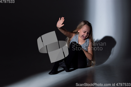 Image of Sad and frightened little girl with bloodshot and bruised eyes sitting scared