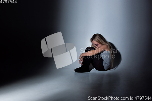 Image of Sad and frightened little girl with bloodshot and bruised eyes sitting scared