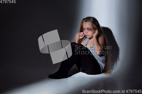 Image of Sad and frightened little girl with bloodshot and bruised eyes sitting scared