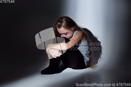 Image of Sad and frightened little girl with bloodshot and bruised eyes sitting scared