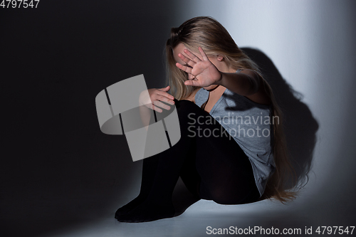 Image of Sad and frightened little girl with bloodshot and bruised eyes sitting scared