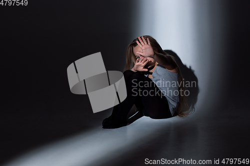 Image of Sad and frightened little girl with bloodshot and bruised eyes sitting scared