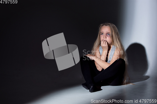 Image of Sad and frightened little girl with bloodshot and bruised eyes sitting scared