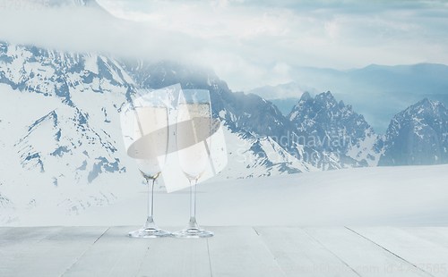 Image of Champagne in glasses and landscape of mountains on background