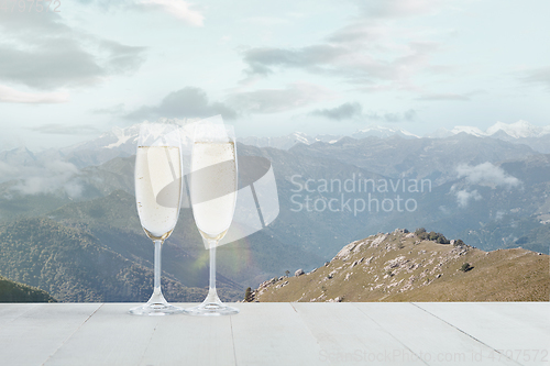 Image of Champagne in glasses and landscape of mountains on background