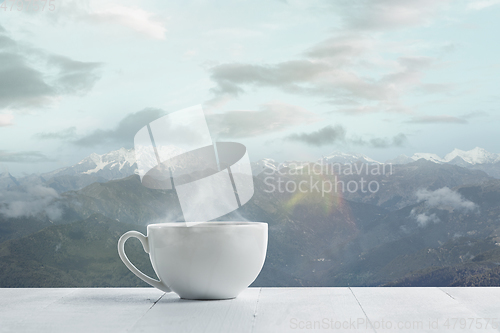 Image of Single tea or coffee mug and landscape of mountains on background