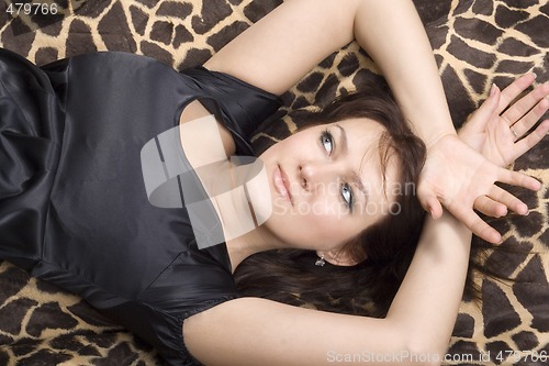 Image of young beauty woman in black dress lies on a bed