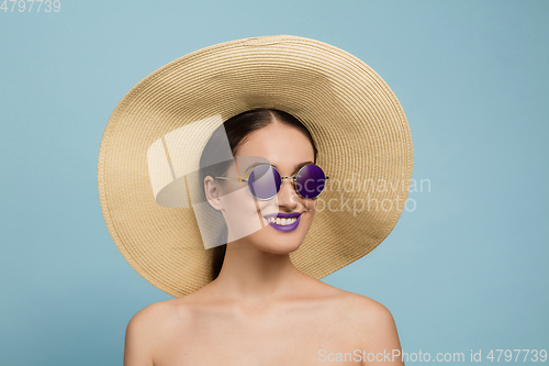 Image of Portrait of beautiful young woman with bright make-up isolated on blue studio background