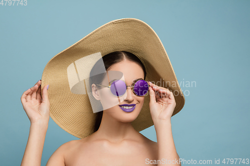 Image of Portrait of beautiful young woman with bright make-up isolated on blue studio background