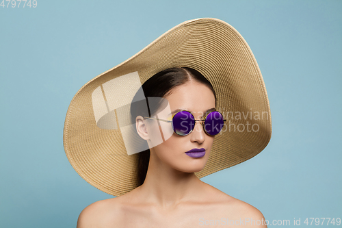 Image of Portrait of beautiful young woman with bright make-up isolated on blue studio background